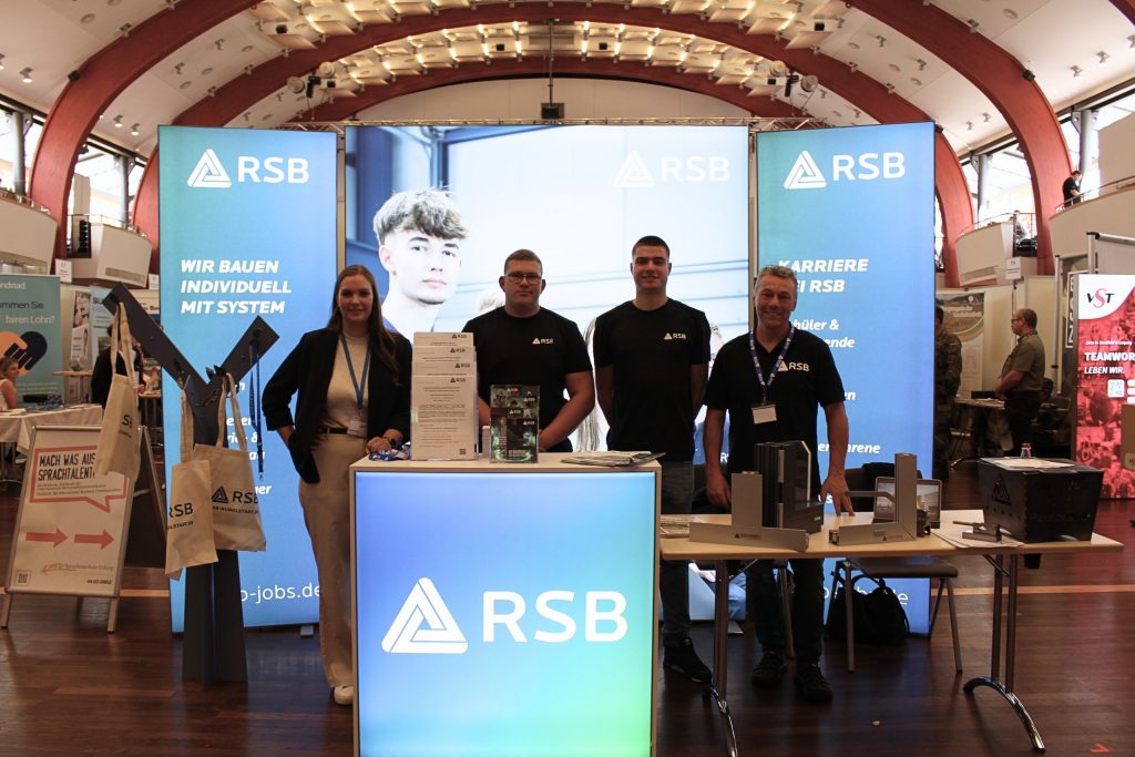 Ausbilder und Azubis mit dem blauen LED-Messestand des RSB auf der InKontakt Messe 2025